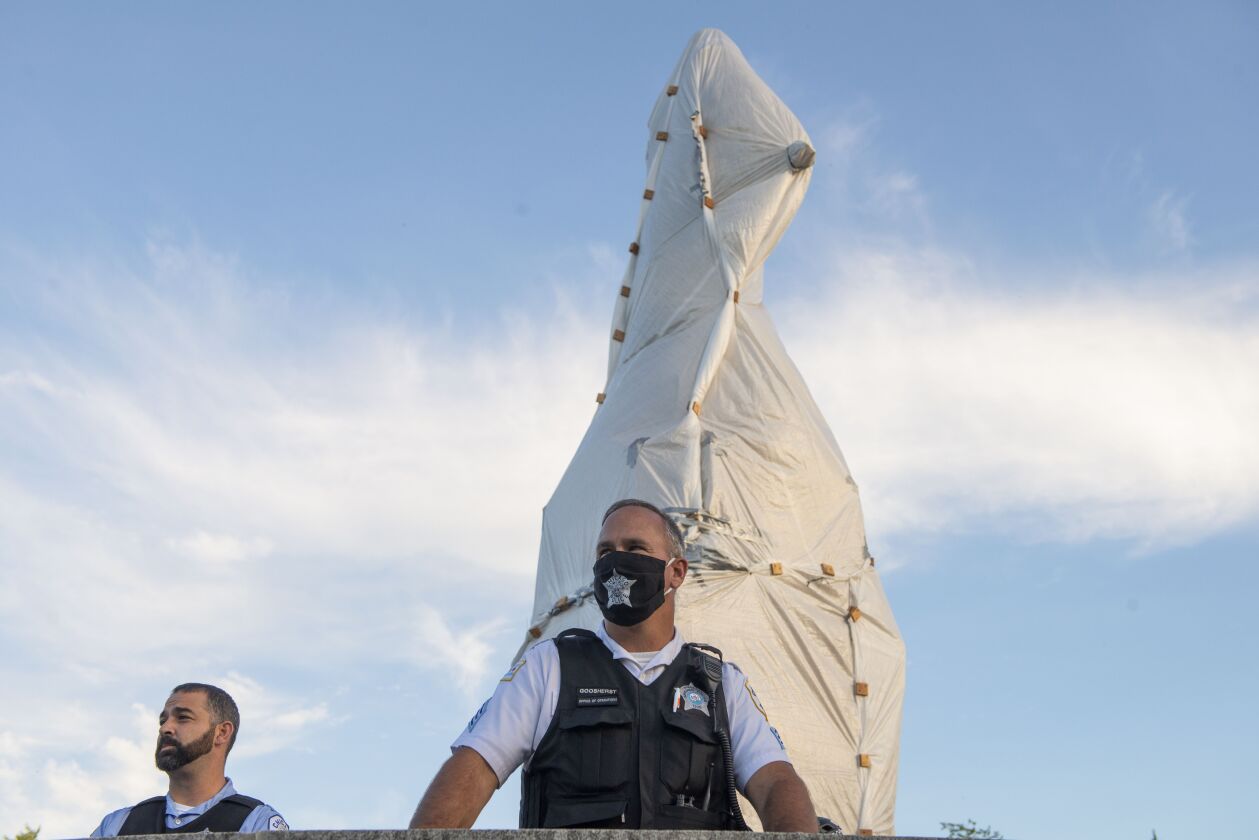 Police surround the Christopher Columbus statue in Grant Park on Friday night after driving away protesters who had tried to take down the statue. During the confrontation, some protesters threw objects at the police, while many protesters reported being beaten, with more than 20 official complaints filed.